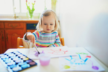 Adorable little girl painting with aquarelle