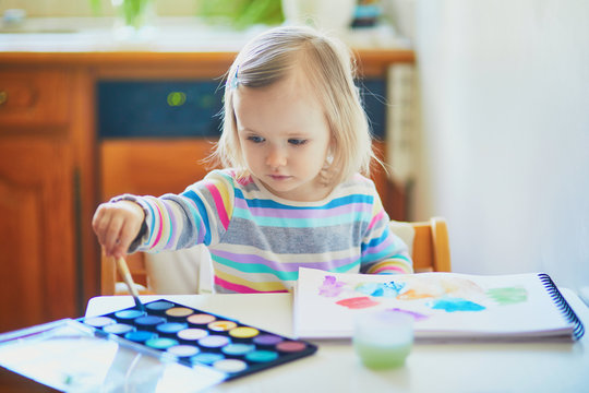 Adorable little girl painting with aquarelle