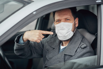 a man driving a car puts on a medical mask during an epidemic, a taxi driver in a mask, protection...