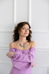 vertical portrait of a beautiful young woman in a purple dress with bare shoulders