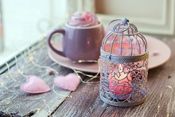 Decorative lantern with candles, a cup of coffee, dessert, romantic decor on a window background, homeliness