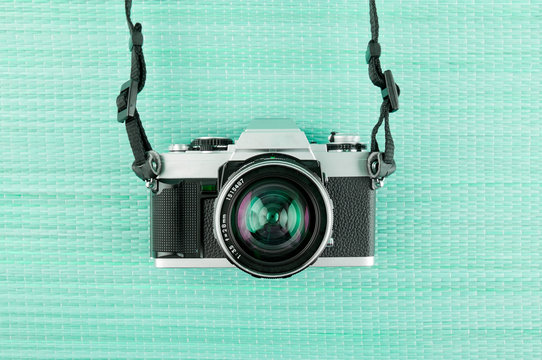 Analog  35mm film slr camera on a green/Aqua Menthe woven background. 