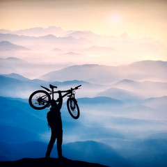 Fototapeta na wymiar Silhouette of cyclist who hold bicycle with one hand