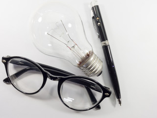 Glasses and black pen and incandescent bulbs on a white background.