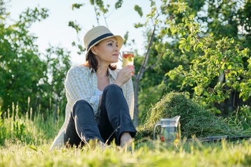 Woman gardener in hat sitting with homemade natural drink mint strawberries