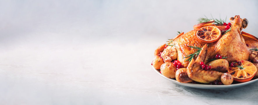 Whole roasted chicken with oranges, cranberries, spices and herbs. Copy space. Friends or family dinner. Festive Christmas table. Traditional Thanksgiving or Friendsgiving holiday celebration dish.