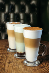 Three types of latte drink in cafe. Classic, caramel and mint latte. Vertical photo.