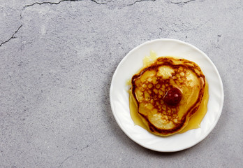 Pancakes with honey and raspberries on a round plate on a light gray background. Top view, flat lay .