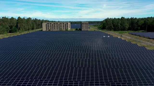 Drone footage panoramic shot of solar power station in Templin, Germany. Car is being driven in the background beetween solar panels and post-soviet buildings.