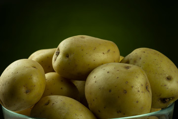 yellow potato lies in a bowl on green background