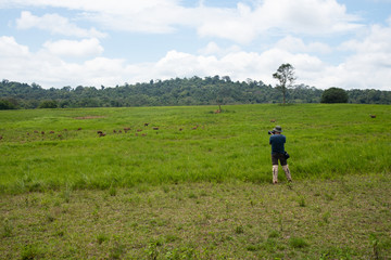 Fototapeta na wymiar Professional photographer take a photo with green grassland and mountain background