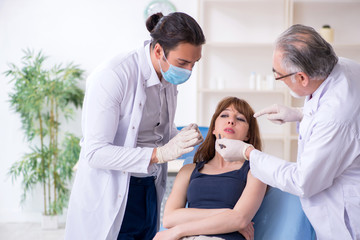 Two male doctors and young woman in plastic surgery concept