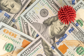 Obraz na płótnie Canvas Coronavirus model on the background of hundred-dollar American banknotes. The concept of the impact of the coronavirus epidemic on financial stability in the world.