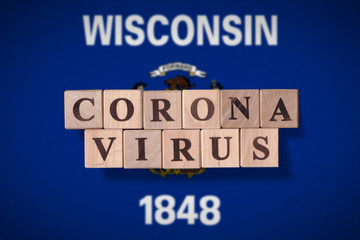 Flag of the state of Wisconsin with wooden cubes spelling coronavirus on it. 2019 - 2020 Novel Coronavirus (2019-nCoV) concept, for an outbreak occurs in Wisconsin, US.