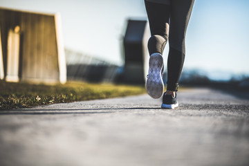 Close up of women's legs running on asphalt road