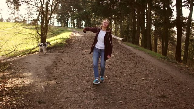 Front view, girl turns around. Young woman is walking along a road in a park with her dog. Walk with a dog during karatentin. Happy family weekend