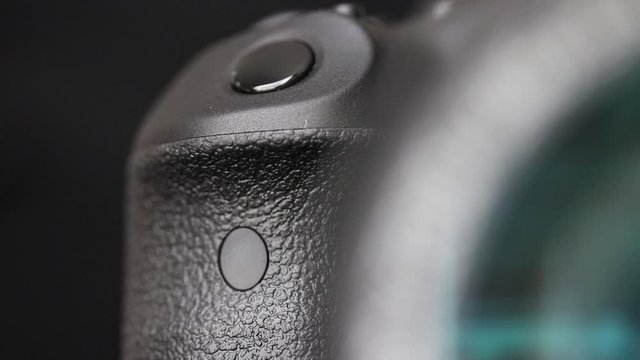Gradual focusing from the lens to the grip with shutter button on the digital camera, a black background.