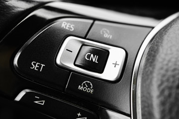 Modern black steering wheel with multifunction buttons for quick control, close-up in the car.