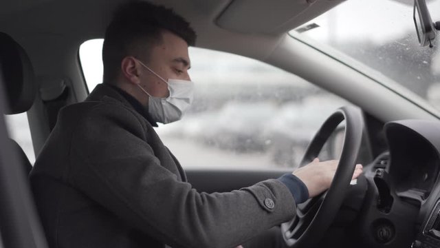 Young business man in the face wask wiping the car sharing wheel during the quarantine pandemic of coronavirus