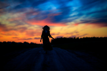 a girl runs along a field road without touching the ground in the evening at sunset a silhouette against the multicolored sky 2