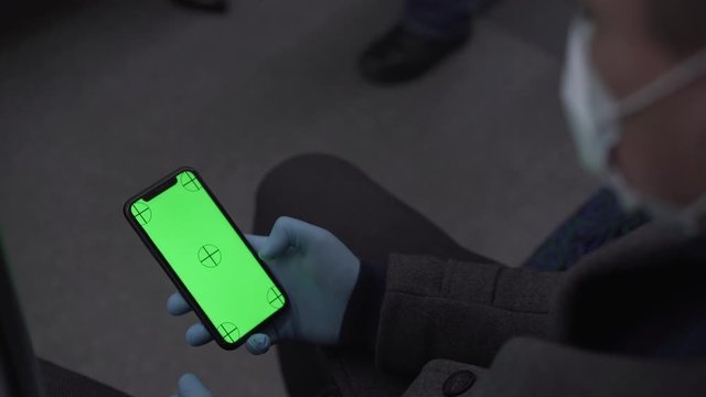 Phone green screen with tracking markers in medical gloves man in the coat in the transport wearing face mask
