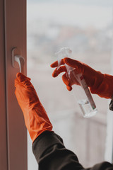 Close-up of gloved hands washing a window, treating the surface with a sanitizer and antiseptic against virus