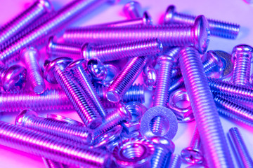 Metal bolts and nuts  in a row background. Chromed screw bolts and nuts in blue and pink tones. Steel bolts and nuts pattern. Set of Nuts and bolts. Tools for work.