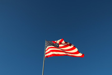 Fototapeta premium American flag waving in the wind with blue sky background