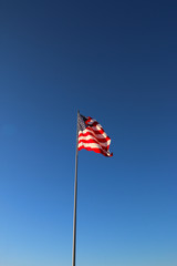 Fototapeta premium American flag waving in the wind with blue sky background