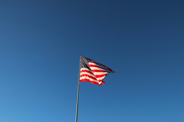 American flag waving in the wind with blue sky background