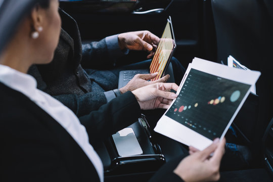 Multiracial colleagues using digital tablet while discussing project and revising documents in car