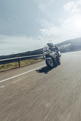 Vertical view of unknown biker couple traveling on motorcycle by road