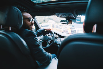 Cheerful executive black businessman driving car