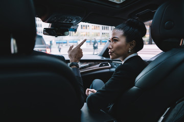 Focused ethnic businesswoman talking with colleague in car
