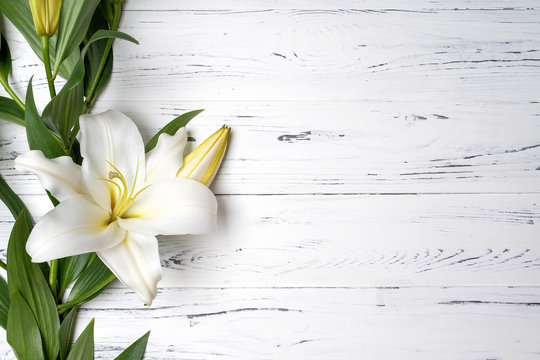 composition of white lilies on a light wooden background .