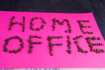 Home office made of coffee beans laid on a pink background