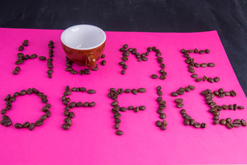 Home office made of coffee beans laid on a pink background