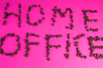 Home office made of coffee beans laid on a pink background