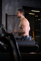 Fototapeta na wymiar Sexy muscular young man running on the treadmill at the gym
