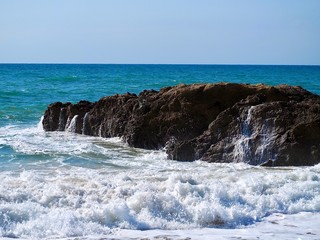 Nature photo of rocks with waves in blue ocean