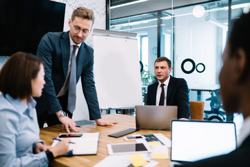 Multiethnic businessmen listening opinion of colleague during negotiation in office