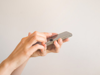 Female hands cleaning smartphone with sanitizer gel over bright gray background