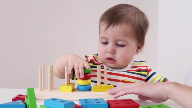Toddler stacking educational pyramid wooden toy and building blocks. One year old baby playing at home