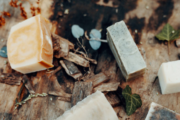 Various handmade natural soaps on a vintage wooden table with decoration