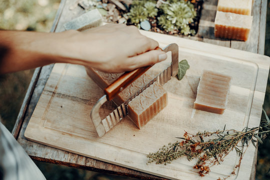 Woman is making handmade natural soaps on an old wooden table