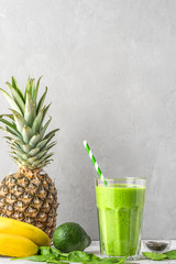 Raw vegan healthy drink. Green smoothie detox in a glass with a straw made of spinach, pineapple,...