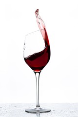 Close up view of splashing red wine in glass isolated on white background. 