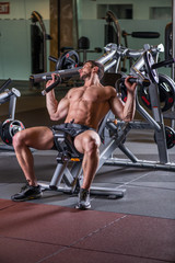 Fototapeta na wymiar Sexy young muscular man doing upper chest exercise on the machine