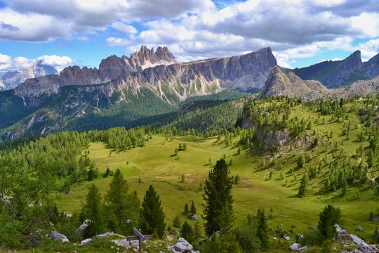 Dolomites mountains, Italy. Sunny day, blue sky, white clouds, green grass. 