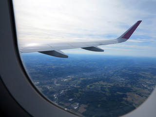 Obraz premium view from the wing of the plane to the ground and to the blue cloudy sky
